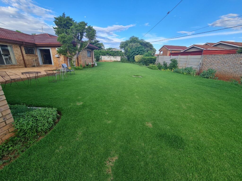 Lush green garden at Quereba Bed and Breakfast Mafikeng with flowers, pathways, and outdoor seating.