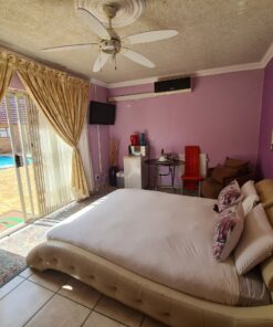 Diamond Deluxe Suite bedroom with warm tones, queen bed, and nearby pool access at Quereba Bed and Breakfast Mafikeng.