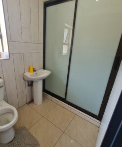 Opal Suite private bathroom with white tiles and bright vanity inside Quereba Guesthouse Mafikeng.
